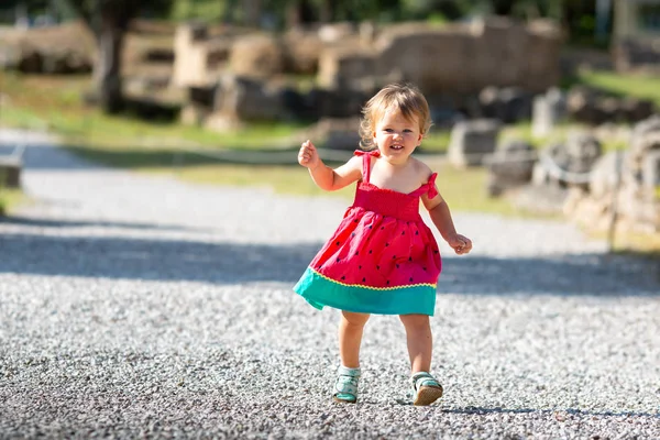Lief blond klein babymeisje in mooie jurk speelt wandelingen buitenshuis — Stockfoto