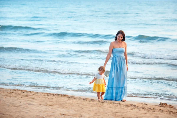 Молодая мама и ее симпатичная маленькая девочка играют на красивом пляже — стоковое фото