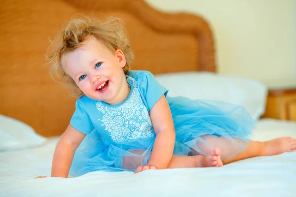 Adorável menina criança loira feliz sentada em uma cama — Fotografia de Stock