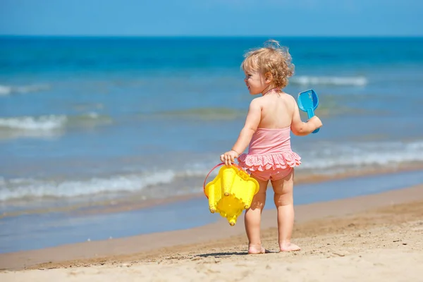 Dítě hrající na tropické pláži. Malá dívka kopání písku, shore na moři. Děti si hrát s hračkami na písek. Cestování s malými dětmi — Stock fotografie