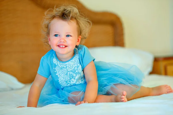 Adorável menina criança loira feliz sentada em uma cama — Fotografia de Stock