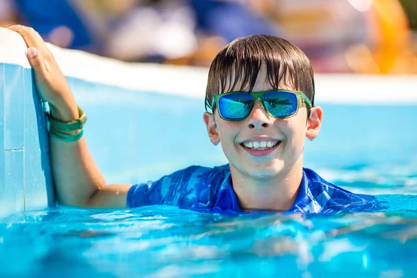 Young boy in googles holding edge of swimming pool. Enjoying time in the refreshing water — Stock Photo, Image