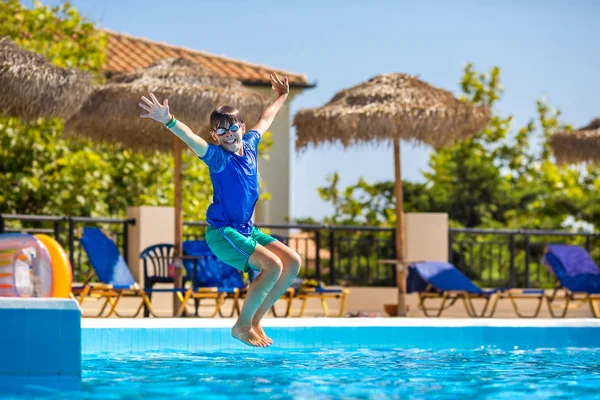 Little cheerful boy jumping to the pool and making water splash, enjoying time in the refreshing water — Stock Photo, Image