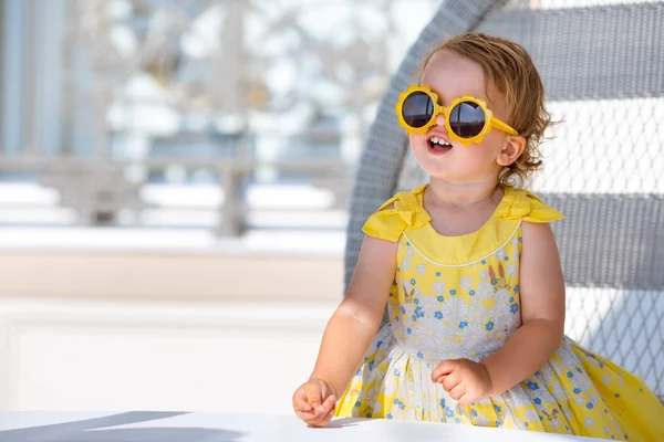 Hermosa niña rubia feliz niño sentado en la cafetería al aire libre —  Fotos de Stock