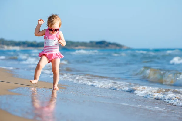 Jolie petite fille bouclée jouant sur une belle plage tropicale portant un maillot de bain mignon — Photo