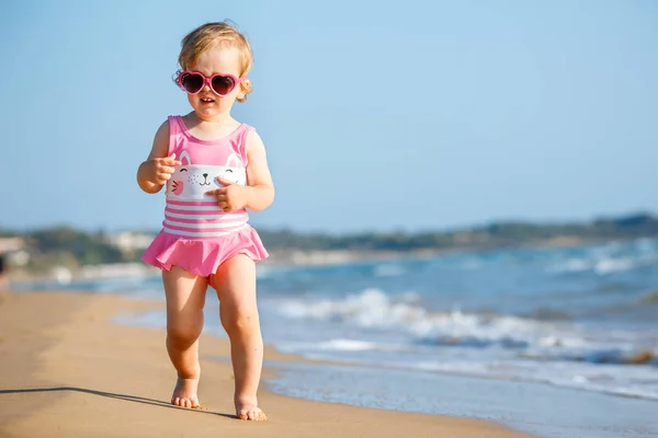 Schattige krullend babymeisje spelen op een prachtig tropisch strand dragen een schattig badpak — Stockfoto