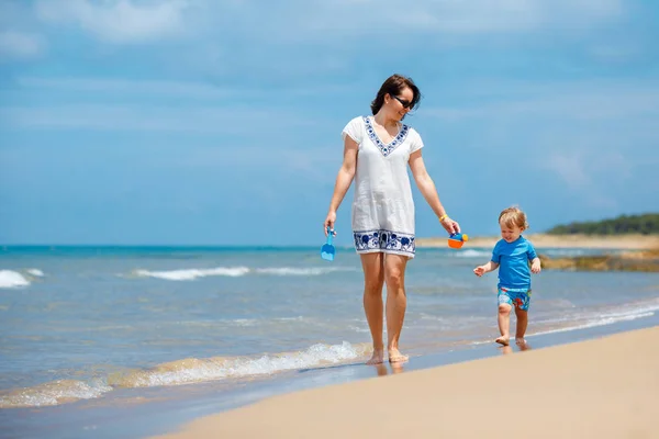 Молодая мама и ее симпатичная маленькая девочка играют на красивом пляже Стоковое Фото