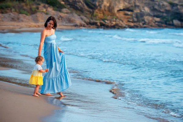 Junge Mutter und ihr süßes kleines Mädchen spielen an einem wunderschönen tropischen Strand lizenzfreie Stockfotos