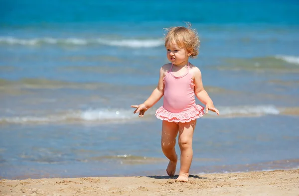 Jolie petite fille bouclée jouant sur une belle plage tropicale portant un maillot de bain mignon Images De Stock Libres De Droits