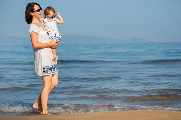 Junge Mutter und ihr süßes kleines Mädchen spielen an einem wunderschönen tropischen Strand lizenzfreie Stockbilder