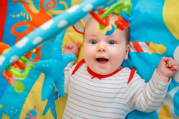 Adorável bebê menina se divertindo com brinquedos no tapete de jogo colorido — Fotografia de Stock