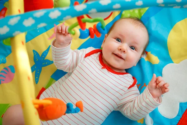 Adorable niña divirtiéndose con juguetes en colorida alfombra de juego — Foto de Stock