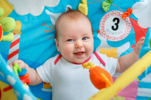 Adorable baby girl having fun with toys on colorful play mat — Stock Photo, Image