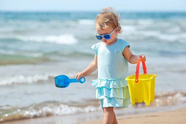 Kind spielt am tropischen Strand. kleines Mädchen, das am Meeresufer Sand gräbt. Kinder spielen mit Sandspielzeug. Reisen mit kleinen Kindern — Stockfoto