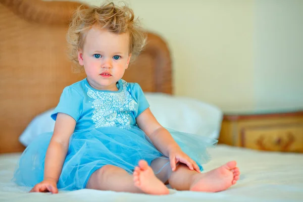 Lovely sleepy blonde toddler girl sitting on a bed — Stock Photo, Image