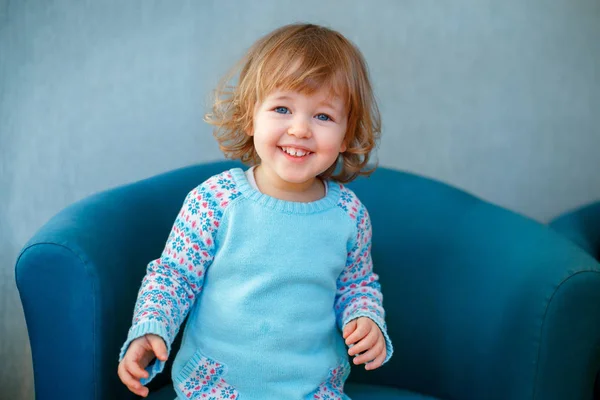 Retrato de niña adorable con el pelo rubio rizado en ropa casual posando en el interior —  Fotos de Stock