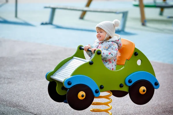 Adorabile bambina seduta in una macchina di legno sul parco giochi all'aperto — Foto Stock