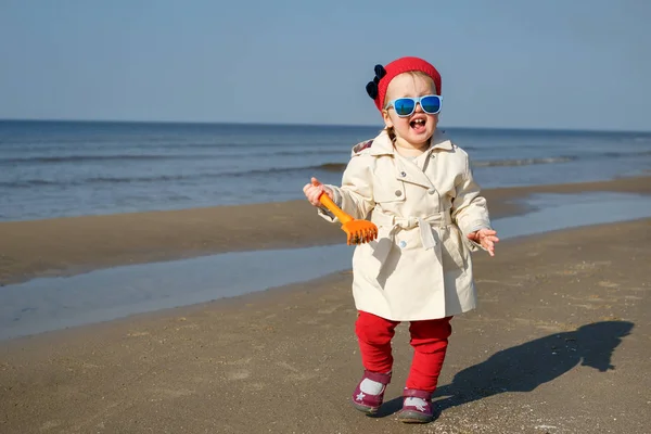 Szczęśliwa dziewczynka uruchomiona na plaży nad Morzem Bałtyckim na Łotwie. Dzieci grają w ocean sand dunes na zimnej jesieni lub wiosny dzień — Zdjęcie stockowe