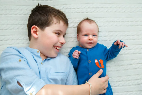 大哥哥抱着他的新生女婴。孩子遇见新的兄弟姐妹 免版税图库照片