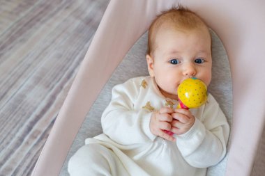 Sevimli bebek kız fedai eğleniyor. Toddler renkli çıngıraklı oyuncak ile oynuyor. Bebekler için aktiviteler