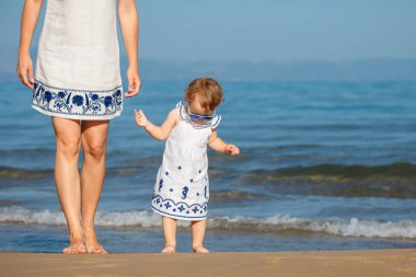 Genç anne ve güzel bir tropik sahilde oynarken onun sevimli küçük bebek kız