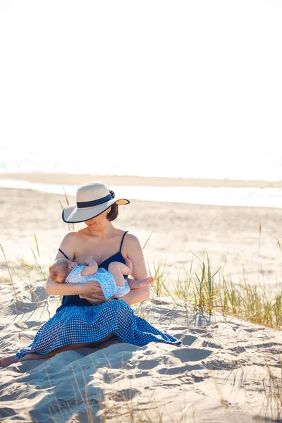 Young mother holding her newborn child. Mom nursing baby in nature — ストック写真