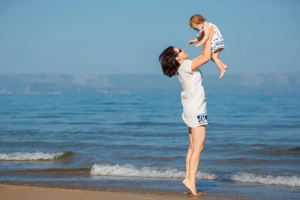 Genç anne ve güzel bir tropik sahilde oynarken onun sevimli küçük bebek kız — Stok fotoğraf