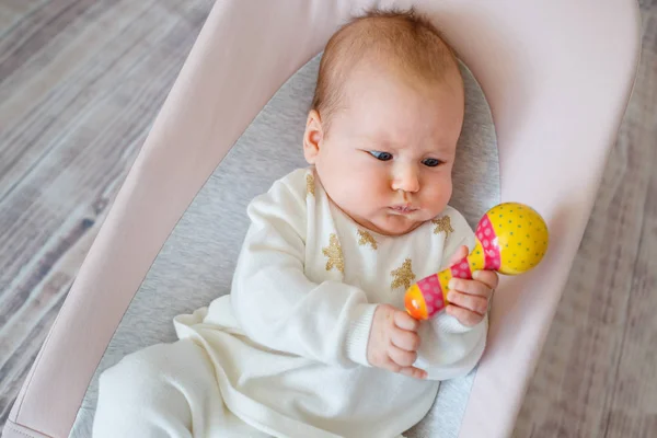 Entzückendes kleines Mädchen, das Spaß im Türsteher hat. Kleinkind spielt mit buntem Rasselspielzeug. Aktivitäten für Kleinkinder Stockfoto