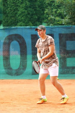 Şapkalı çocuk kortta tenis oynuyor