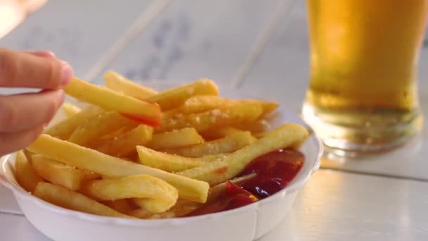 Frites met ketchup en een glas bier — Stockvideo