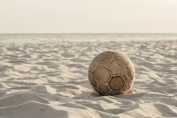 Alter verschlissener Fußball am Strand lizenzfreie Stockfotos