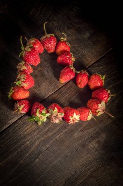 Çilek ahşap arka plan üzerinde kalp şeklinde.