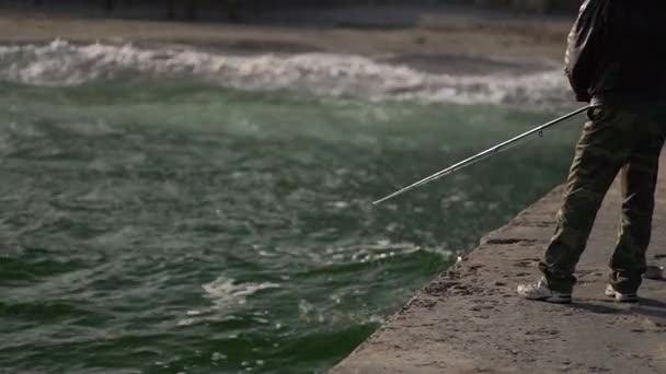 Homem captura peixe no cais junto ao mar . — Vídeo de Stock