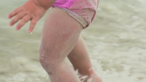 Маленький ребенок плескается в воде на пляже. Медленное движение — стоковое видео
