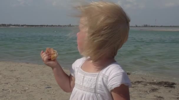 Lilla flickan har frukost på stranden. Ett barn på kusten. Lyckligt glada barn. — Stockvideo