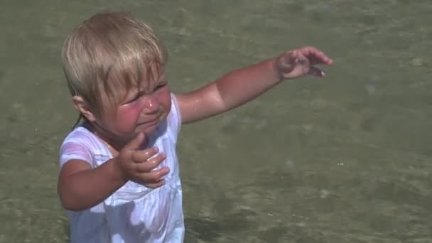 Bebé llorón con los brazos abiertos de pie en el agua . — Vídeo de stock