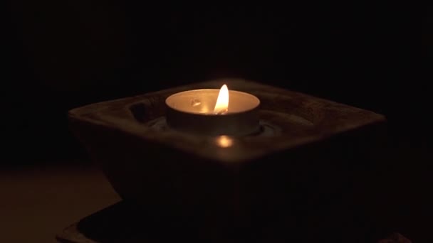 Brinnande ljus i mörkret i en sten ljus stake. — Stockvideo