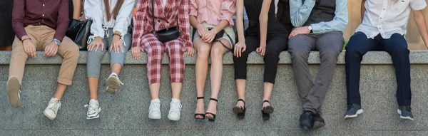 Молоді люди сидять на бетонному парапеті, ряду ніг. Горизонтальний панорамний фото банер для дизайну заголовка веб-сайту . Стокова Картинка