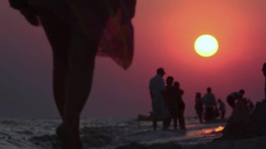 Akşamları deniz kıyısında. İnsanlar gün batımında sahilde.