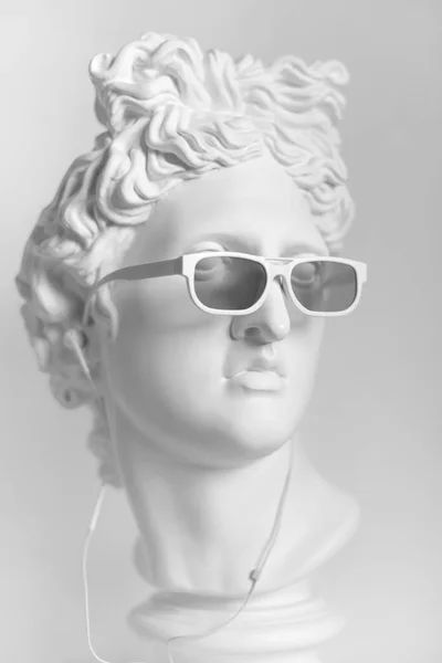 アポロの頭部の石膏像 イヤホンの白いサングラス アポロの頭の像を石膏します — ストック写真