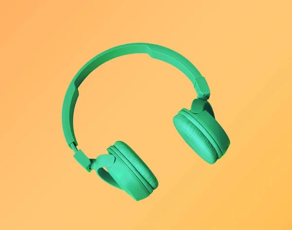 Headphones. Green headphones with on a yellow background. Headphones on yellow background. Sounds.  Music concept.