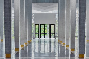 Birçok sütunlar, sonunda açık kapılar, modern salonda simetrik: National Mosque (Mescid Negara), Kuala Lumpur, Malezya arasında uzun koridor. Doğal havalandırma ve aydınlatma ile fonksiyonel iç.