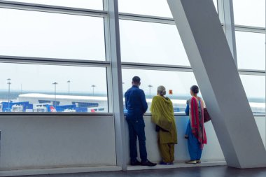 Malezya, Kuala Lumpur, 2018-04-03: Havaalanında uçak pencere bakarak Hint aile üyeleri. Vakit-e kadar uçuş.