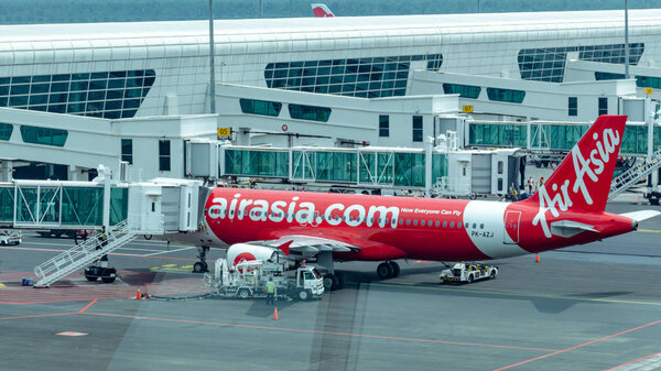 Malaysia, Kuala Lumpur International Airport, 04-03-2018:  Airplane by company Airasia preparing for departure,  jet bridge with passengers, refueling tanks fuel. Airport daily routine.