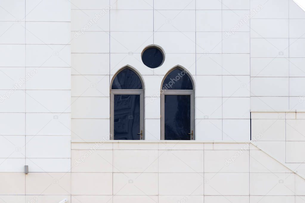 White wall with an arched and round windows, detail of building exterior, urban geometry, copy space.  Abstract minimal style architecture background.