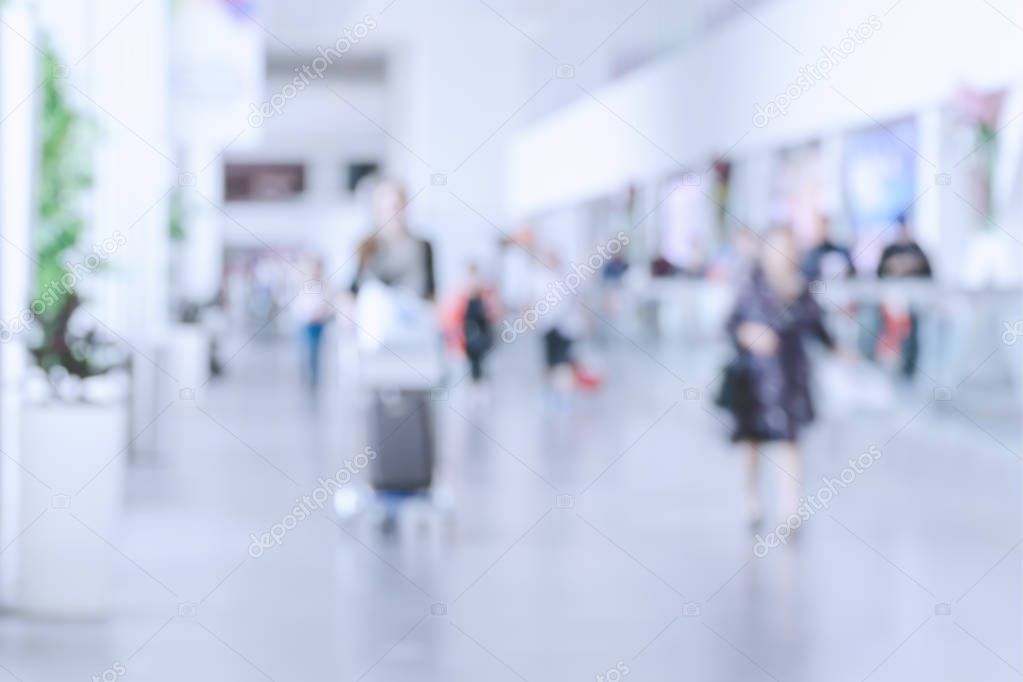 Blurred photo with people at airport, defocused silhouettes indoors, unrecognizable persons, abstract background with crowd, motion blur.