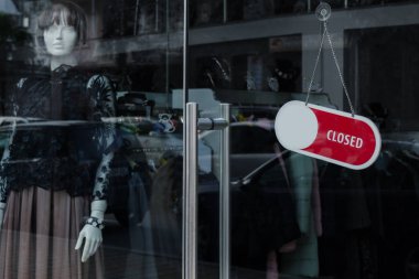 Bir giyim mağazası kapalı işareti olan glassdoor. Vitrin üzerinde kadın manken. Bir dönemde tüketimi, bereket, indirimler sonu kavramı.