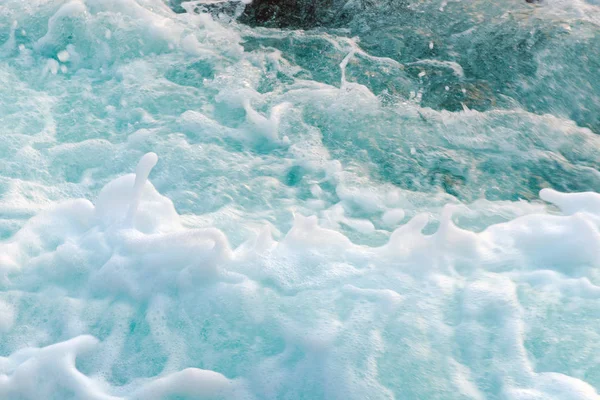 Dense sea foam on the water surface, view from above. Photo with motion blur.