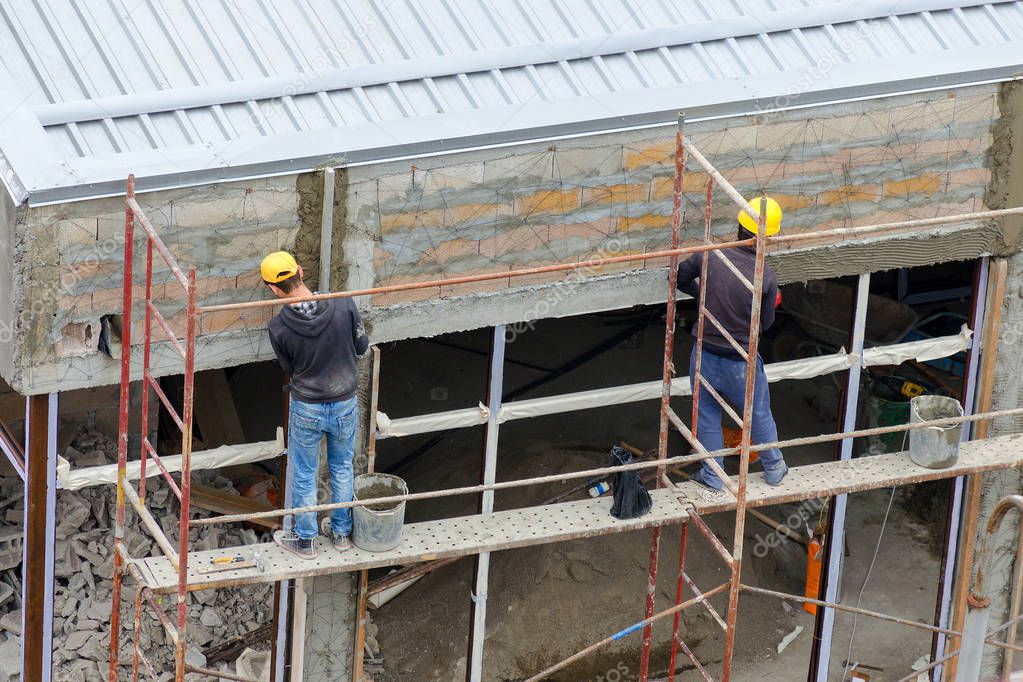 Construction workers plaster wall