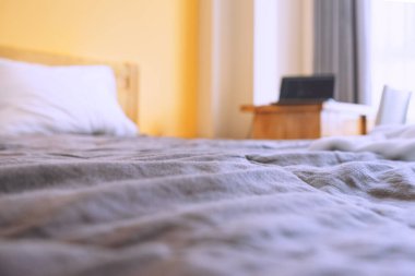 Masada dizüstü bilgisayarı olan bir yatağın bulanık fotoğrafı. Küçük bir dairede iş yeri. Seçici odaklı fotoğraf